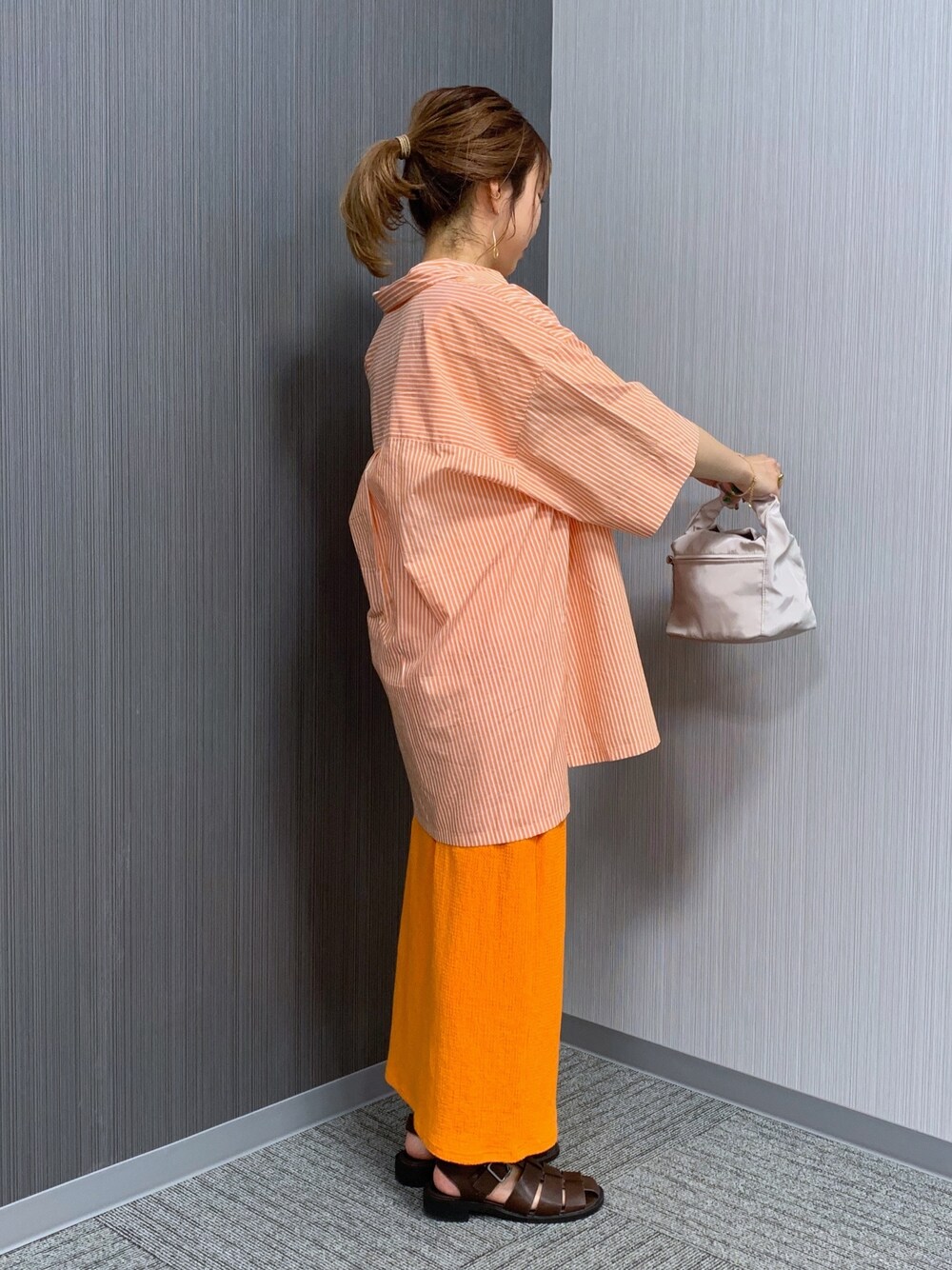 オレンジ系のシャツ/ブラウス、オレンジ系のスカート、ホワイト系のショルダーバッグを着用したレディースの夏コーディネートの5枚目の写真