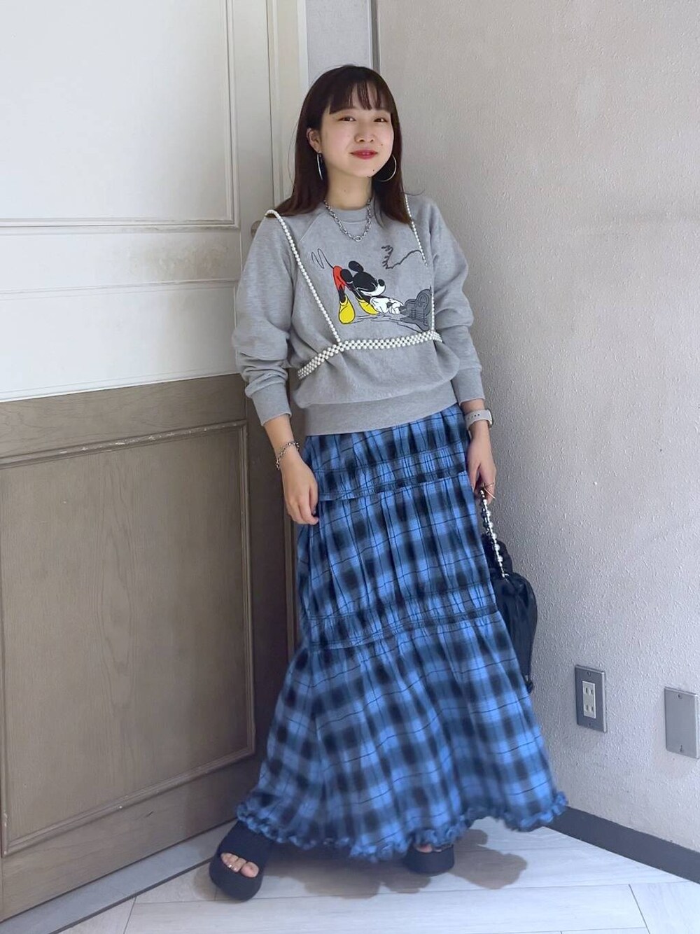 ブラック系のサンダル、ブルー系のスカート、グレー系のスウェットを着用したレディースの夏コーディネートの1枚目の写真