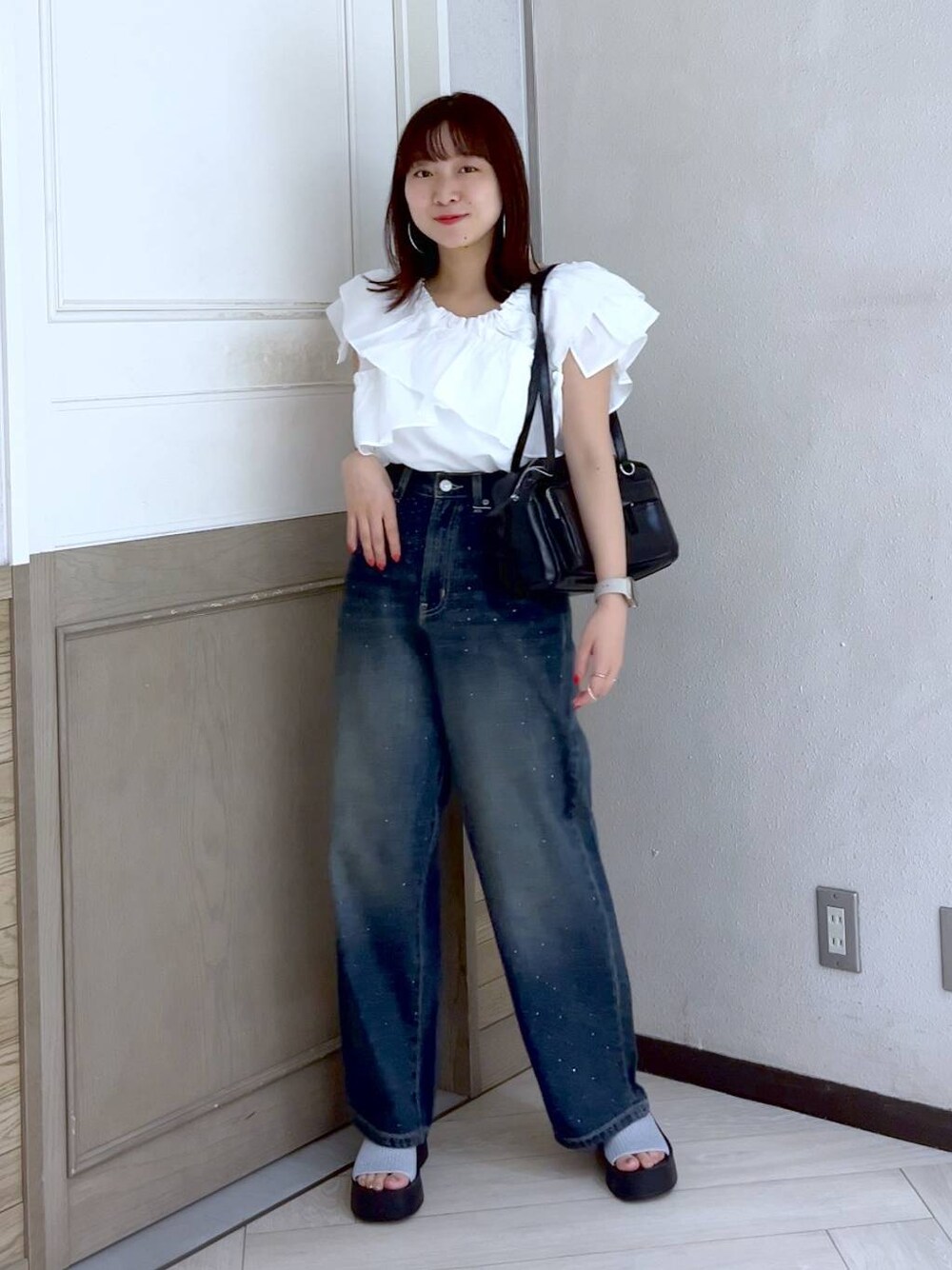 シルバー系のサンダル、ブルー系のデニムパンツ、ブラック系のボストンバッグを着用したレディースの夏コーディネートの1枚目の写真