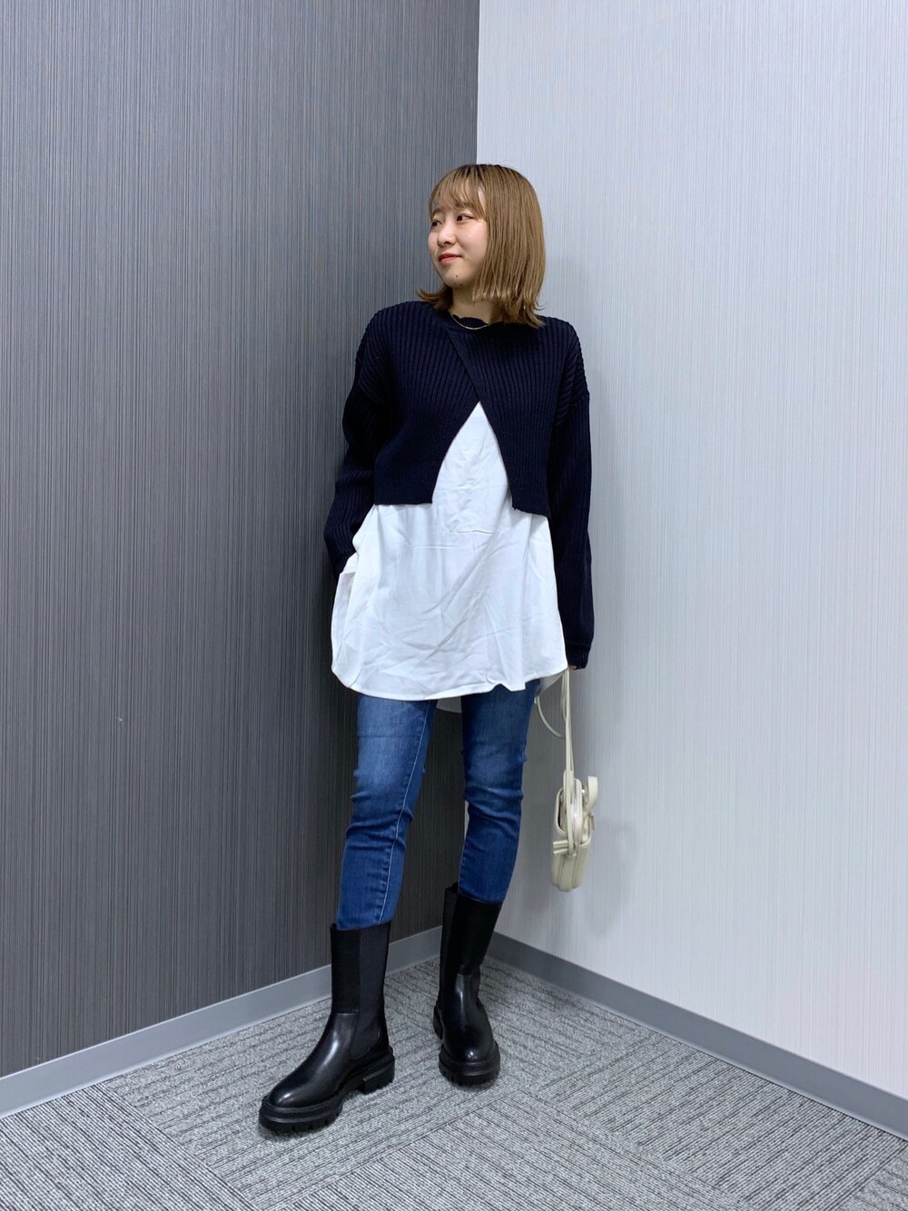 ブラック系のニット/セーター、ブルー系のデニムパンツ、ホワイト系のショルダーバッグを着用したレディースの冬コーディネートの2枚目の写真