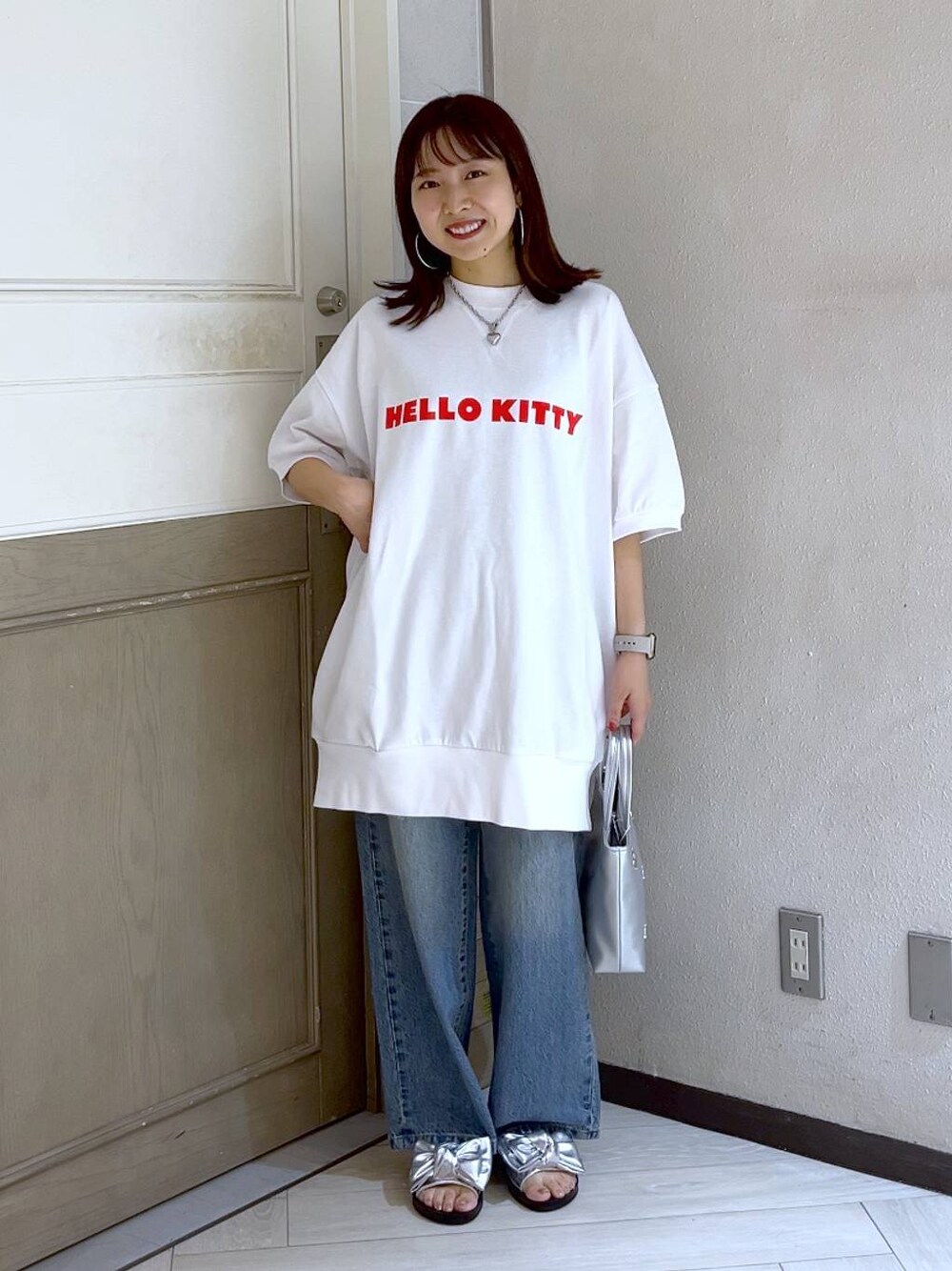 シルバー系のショルダーバッグ、ブルー系のデニムパンツ、シルバー系のサンダルを着用したレディースの夏コーディネートの1枚目の写真