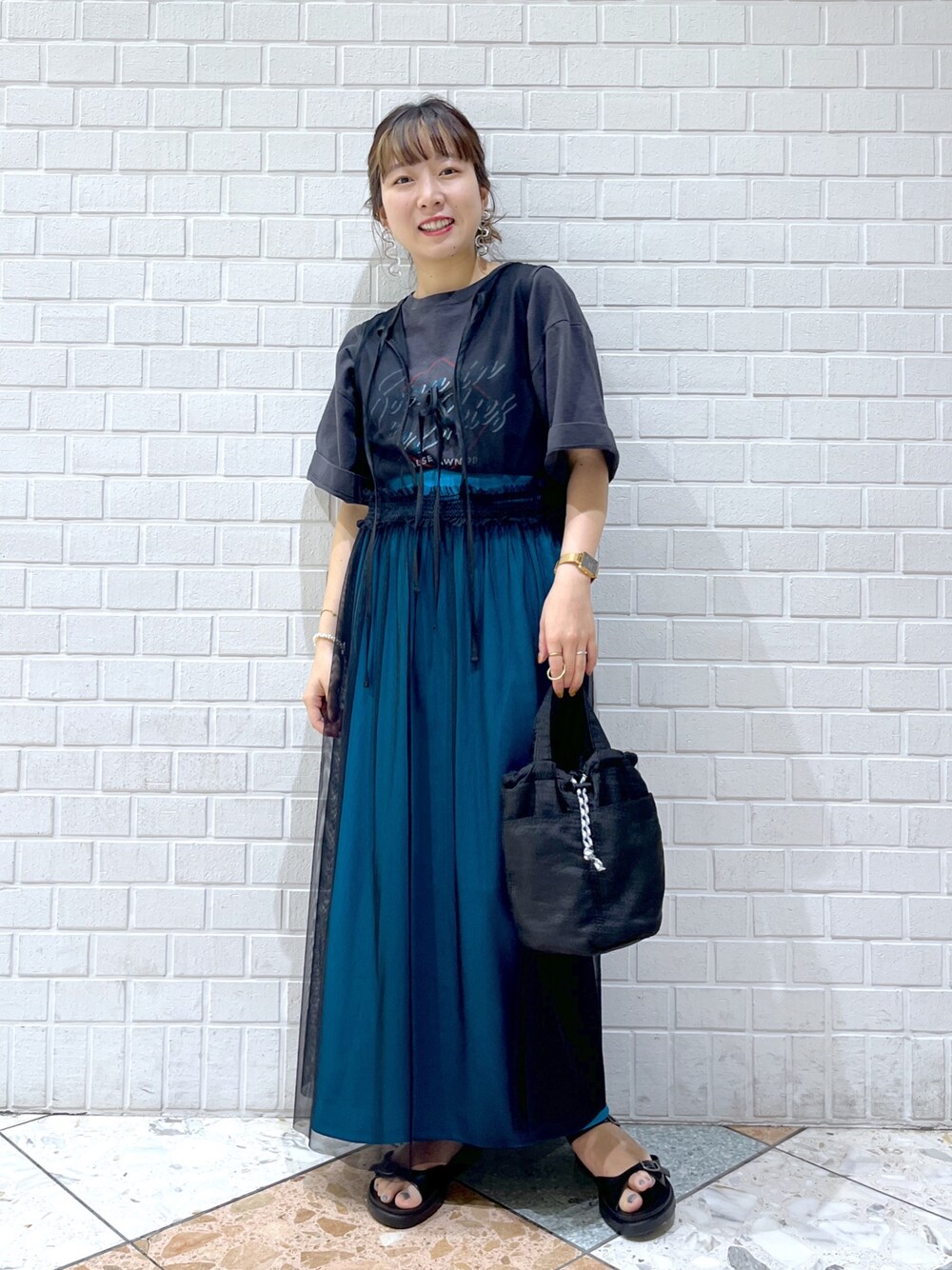 グレー系のTシャツ/カットソー、ブラック系のワンピース、ブルー系のスカートを着用したレディースの春コーディネートの1枚目の写真