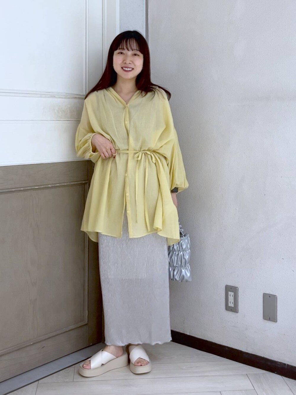 イエロー系のシャツ/ブラウス、ホワイト系のスカート、ホワイト系のサンダルを着用したレディースの夏コーディネートの1枚目の写真