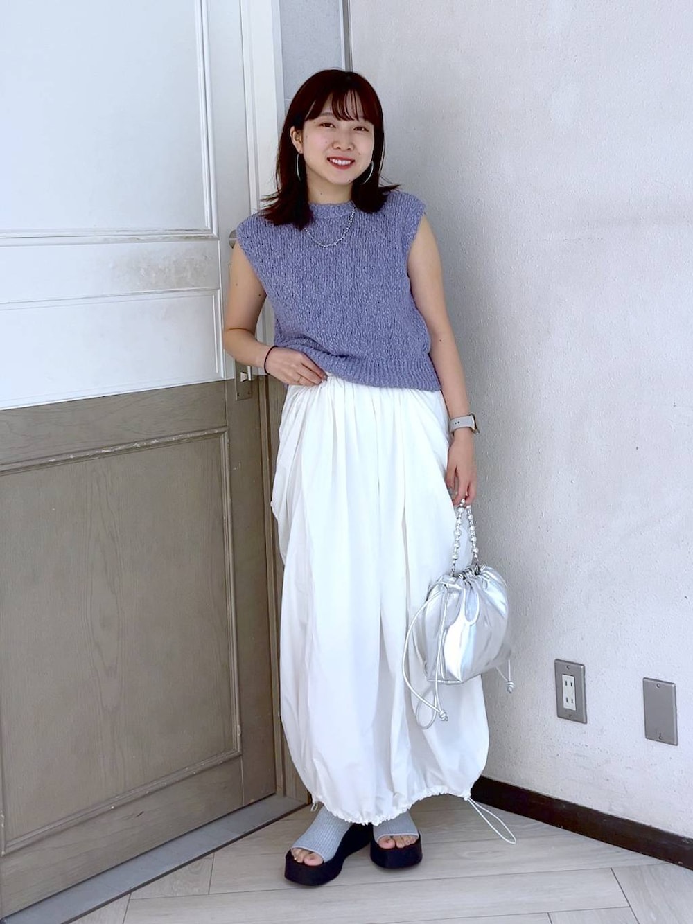 シルバー系のサンダル、ホワイト系のスカート、シルバー系のショルダーバッグを着用したレディースの夏コーディネートの1枚目の写真