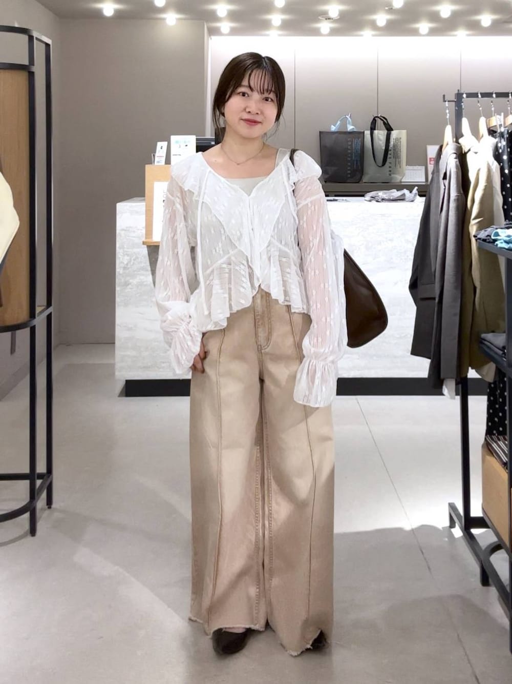 シルバー系のタンクトップ、ブラック系のパンプス、オレンジ系のデニムパンツを着用したレディースの春コーディネートの1枚目の写真