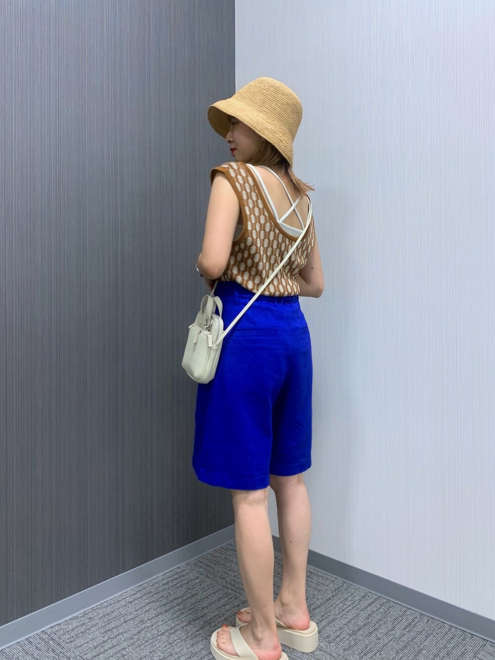 ブラウン系のベスト、ブルー系のその他パンツ、ホワイト系のショルダーバッグを着用したレディースの夏コーディネートの2枚目の写真