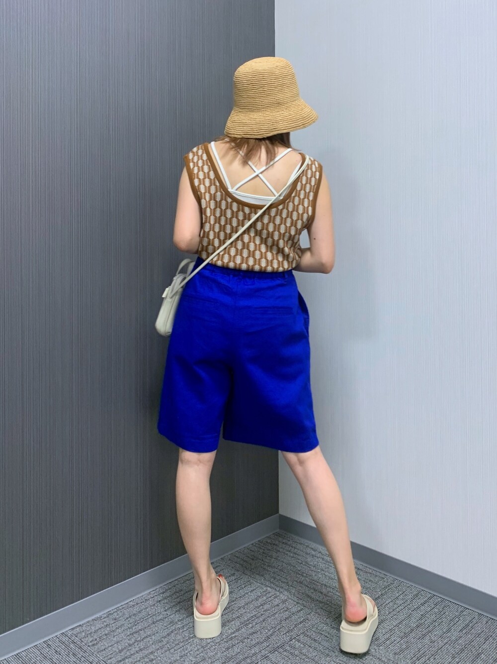 ブラウン系のベスト、ブルー系のその他パンツ、ホワイト系のショルダーバッグを着用したレディースの夏コーディネートの3枚目の写真