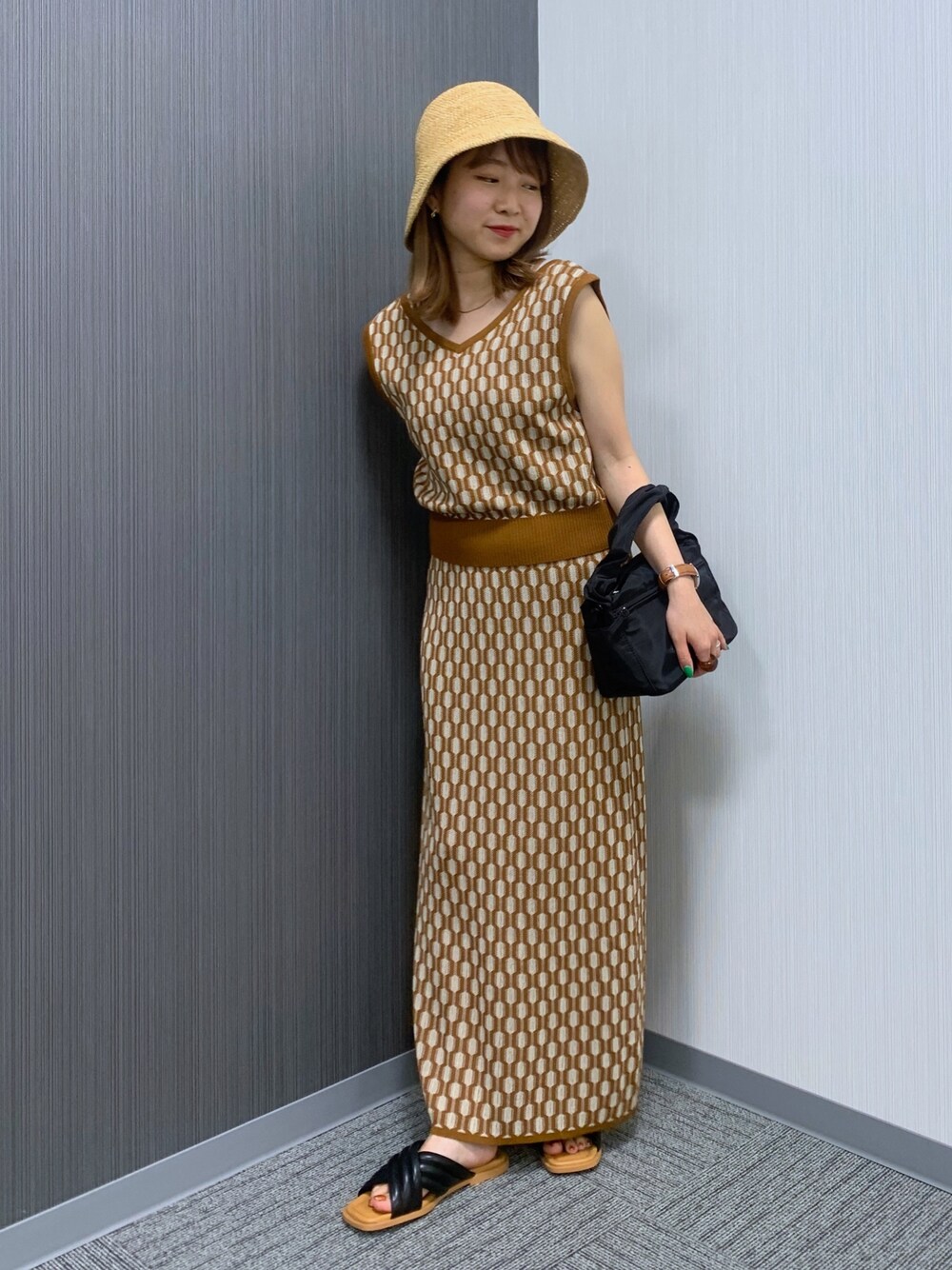 ブラウン系のベスト、ブラウン系のスカート、ブラック系のショルダーバッグを着用したレディースの夏コーディネートの2枚目の写真