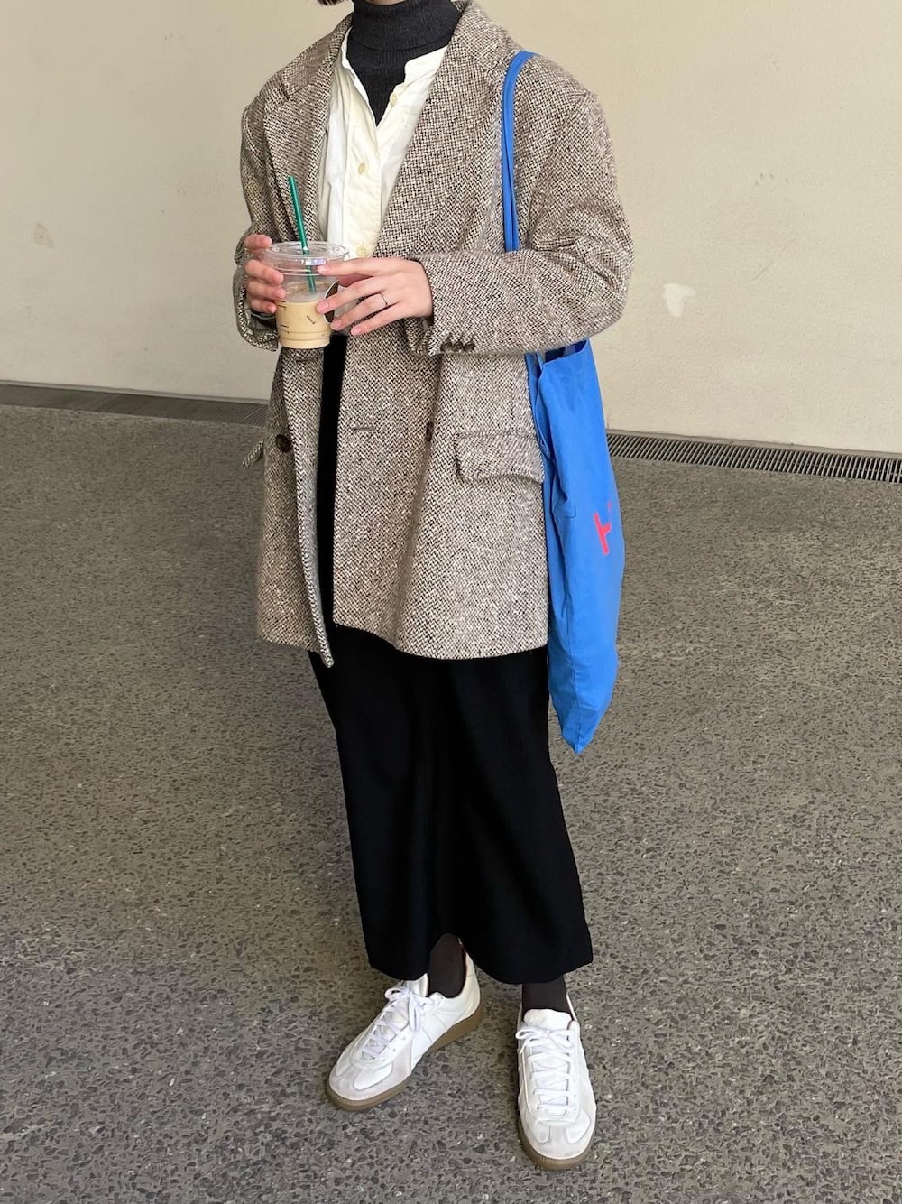 ブラック系のスカート、ホワイト系のスニーカーを着用したレディースの春コーディネートの1枚目の写真