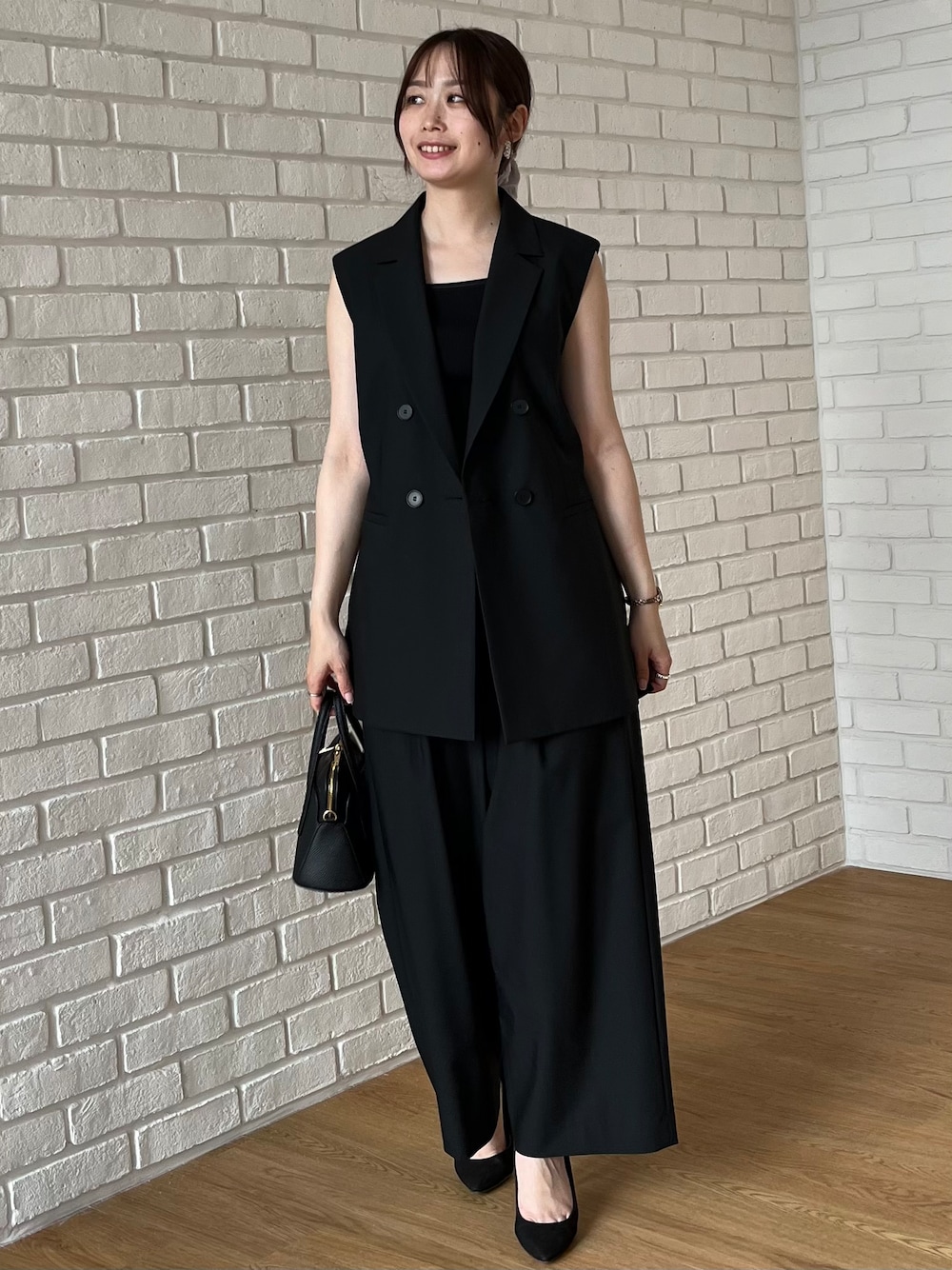ブラック系のニット/セーター、ブラック系のショルダーバッグを着用したレディースの夏コーディネートの1枚目の写真