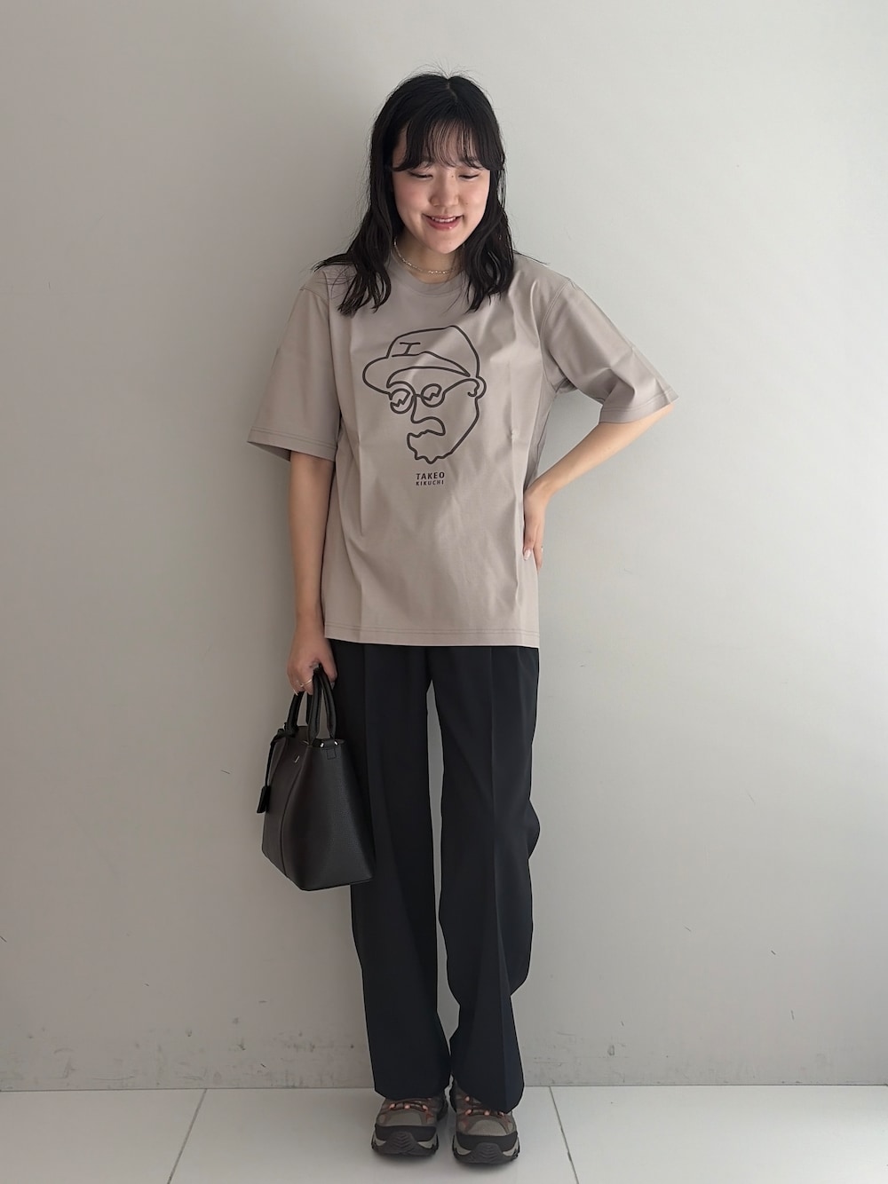 ブルー系のスラックス、ブラック系のトートバッグ、ベージュ系のTシャツ/カットソーを着用したメンズの春コーディネートの1枚目の写真
