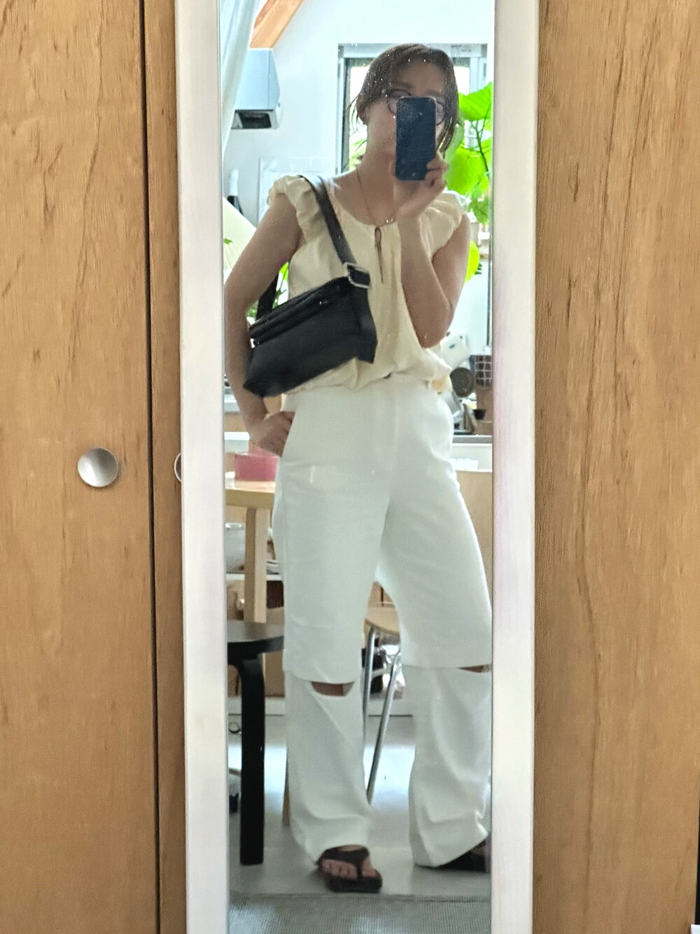 ブラック系のハンドバッグ、ホワイト系のパンツ、ブラック系のネックレスを着用したレディースの夏コーディネートの1枚目の写真