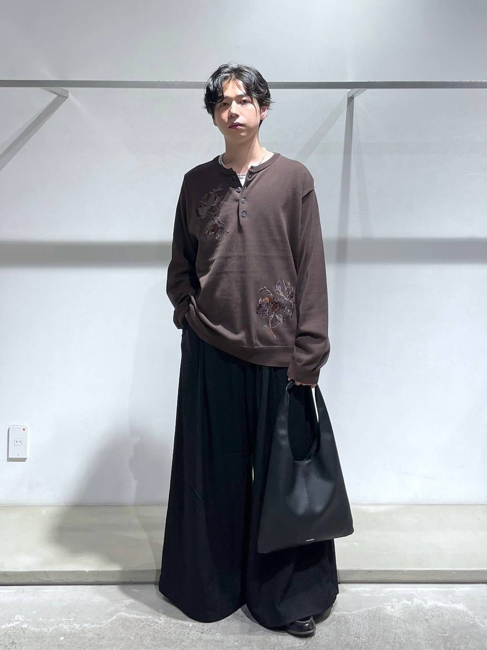 ブラウン系のニット/セーター、ブラック系のトートバッグ、ブラック系のスラックスを着用したメンズの夏コーディネートの1枚目の写真