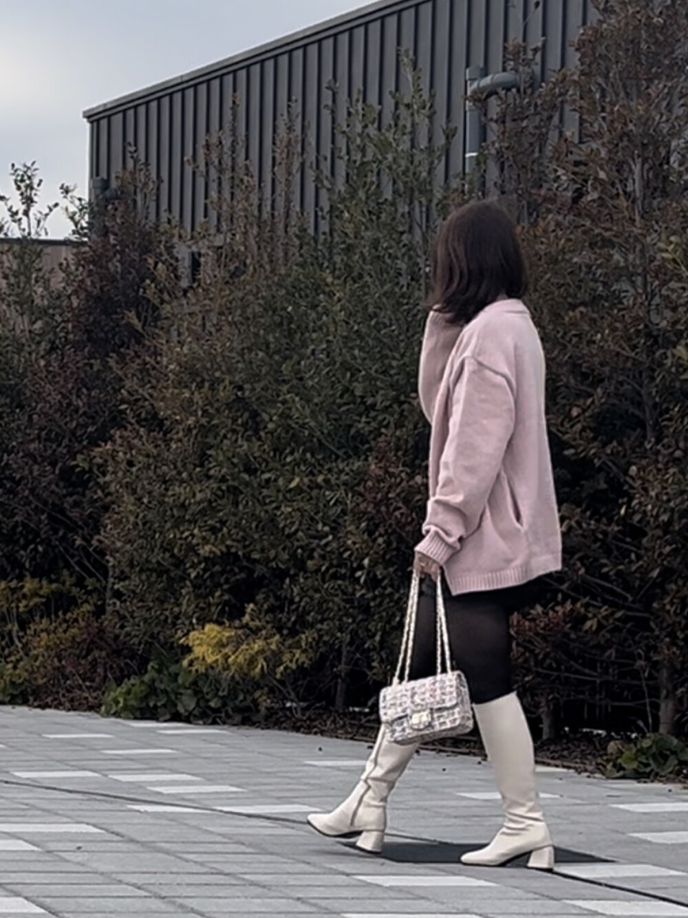 ピンク系のカーディガン/ボレロ、ブラック系のスカート、ホワイト系のショルダーバッグを着用したレディースの冬コーディネートの1枚目の写真