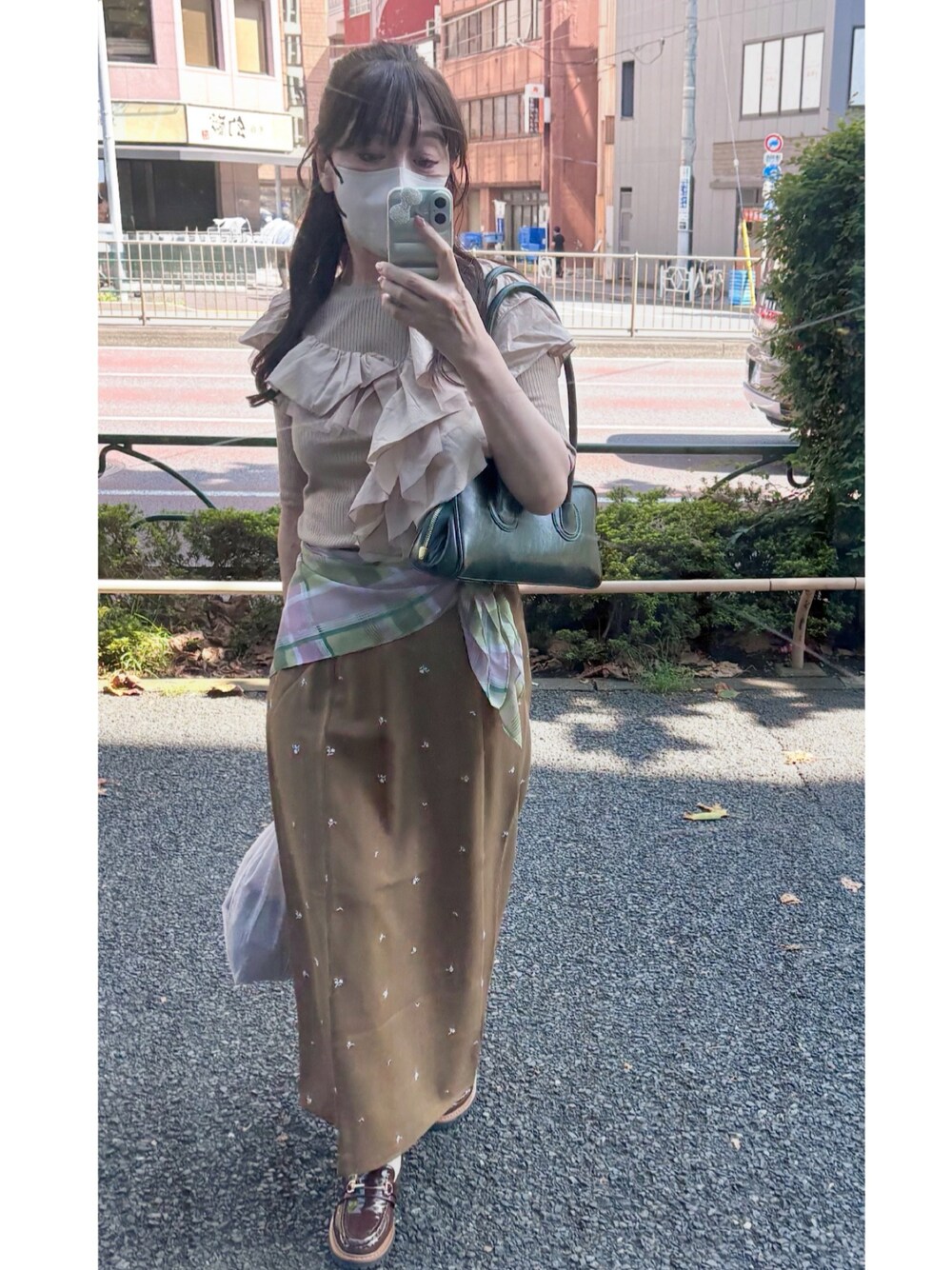 ベージュ系のTシャツ/カットソー、ブラウン系のスカート、グリーン系のショルダーバッグを着用したレディースの秋コーディネートの1枚目の写真