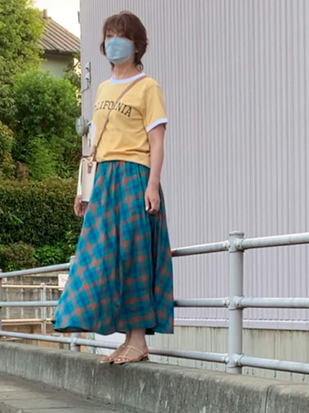 グリーン系のスカート、イエロー系のTシャツ/カットソー、ホワイト系のボディバッグ/ウエストポーチを着用したレディースの夏コーディネートの1枚目の写真