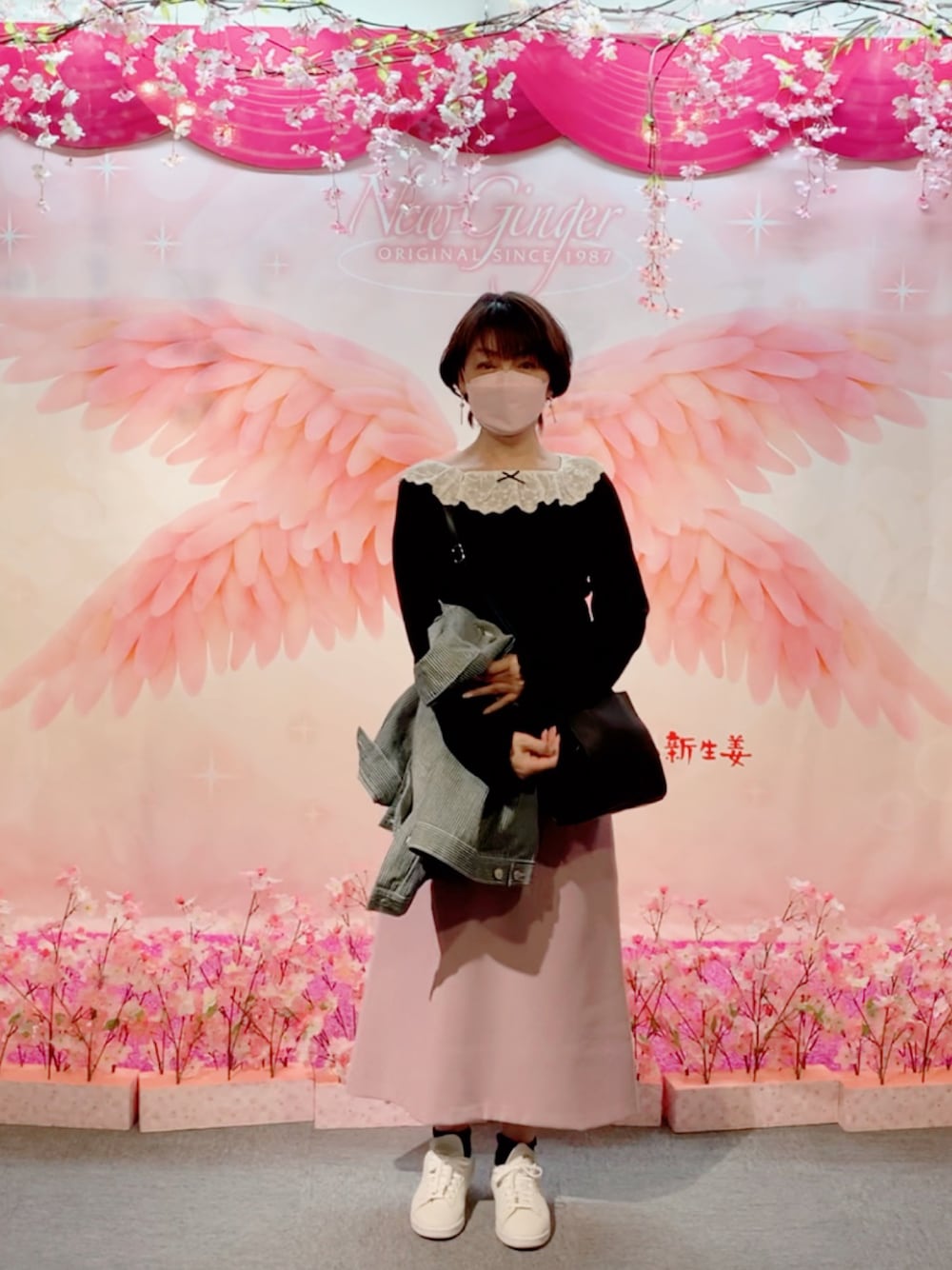 ホワイト系のスニーカー、ピンク系のスカート、ブラック系のショルダーバッグを着用したレディースの春コーディネートの1枚目の写真