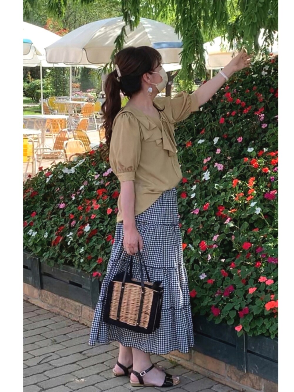 ブラック系のハンドバッグ、ブラック系のスカート、ホワイト系のアナログ腕時計を着用したレディースの夏コーディネートの1枚目の写真