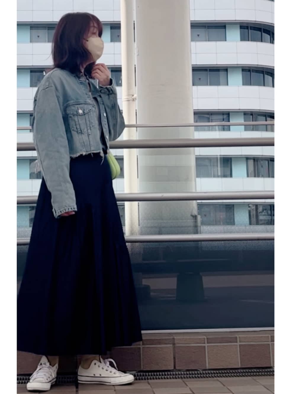 ブルー系のデニムジャケット、ホワイト系のスニーカー、グリーン系のショルダーバッグを着用したレディースの春コーディネートの1枚目の写真