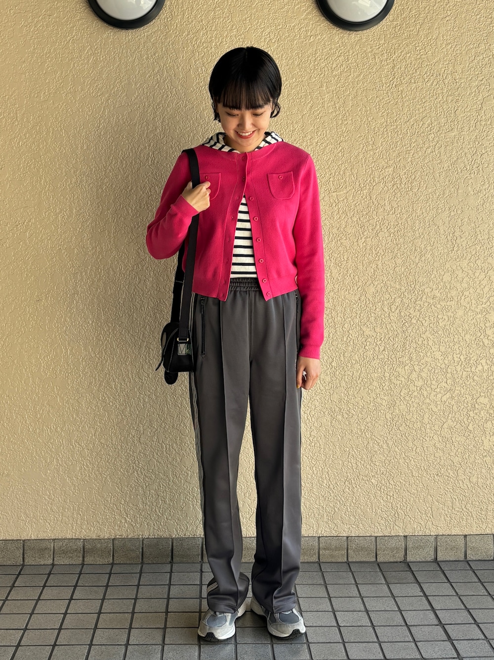 ピンク系のカーディガン/ボレロ、グレー系のパンツ、グレー系のスニーカーを着用したレディースの冬コーディネートの1枚目の写真