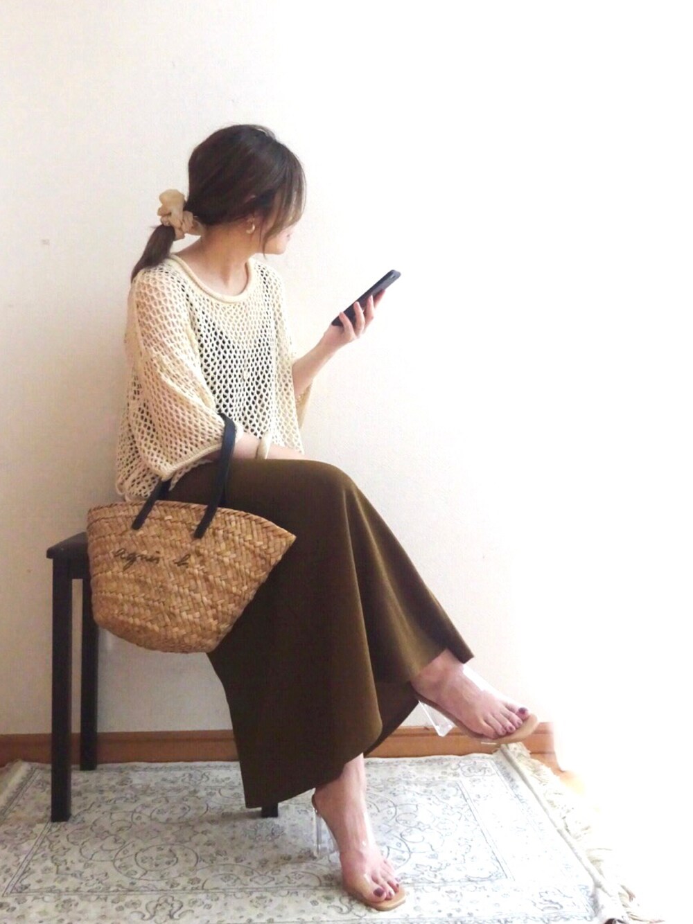ブラック系のかごバッグ、ブラウン系のスカート、ホワイト系のニット/セーターを着用したレディースの夏コーディネートの1枚目の写真