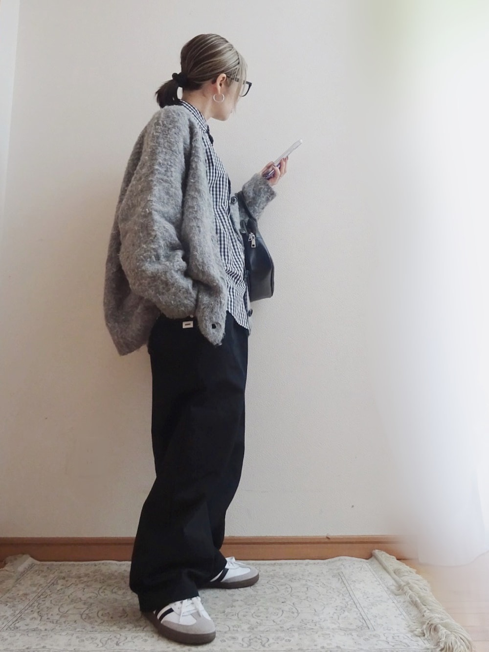 ホワイト系のスニーカー、ブラック系のチノパンツ、グレー系のカーディガン/ボレロを着用したレディースの春コーディネートの1枚目の写真