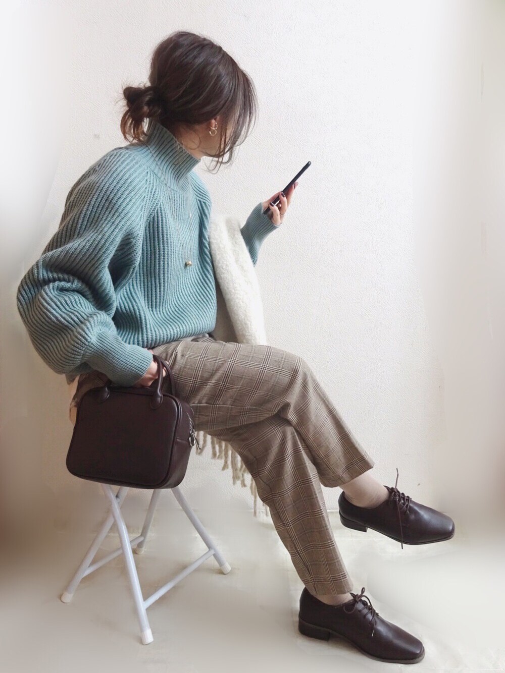 ブルー系のニット/セーター、ブラウン系のボストンバッグ、ベージュ系のパンツを着用したレディースの秋コーディネートの1枚目の写真