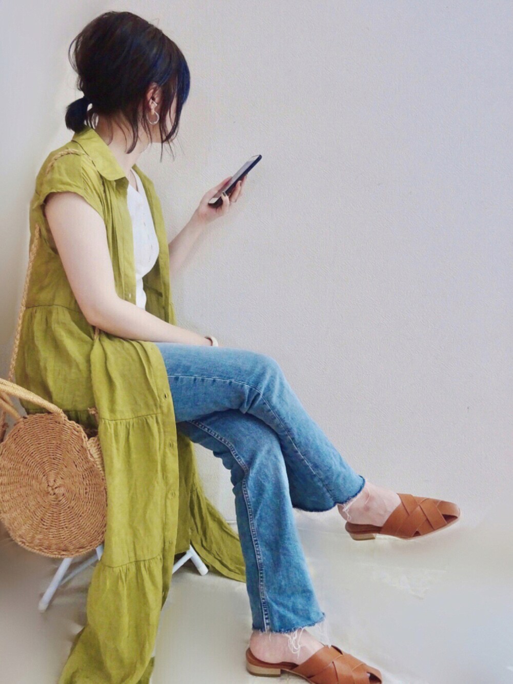 ブルー系のデニムパンツ、グリーン系のワンピース、その他のかごバッグを着用したレディースの夏コーディネートの1枚目の写真