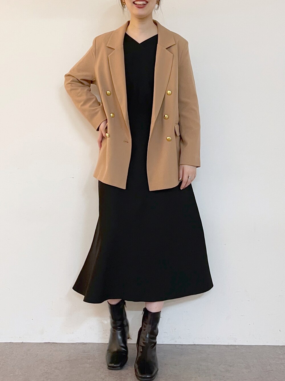 ベージュ系のテーラードジャケット、ブラック系のワンピース、ブラック系のブーツを着用したレディースの夏コーディネートの1枚目の写真