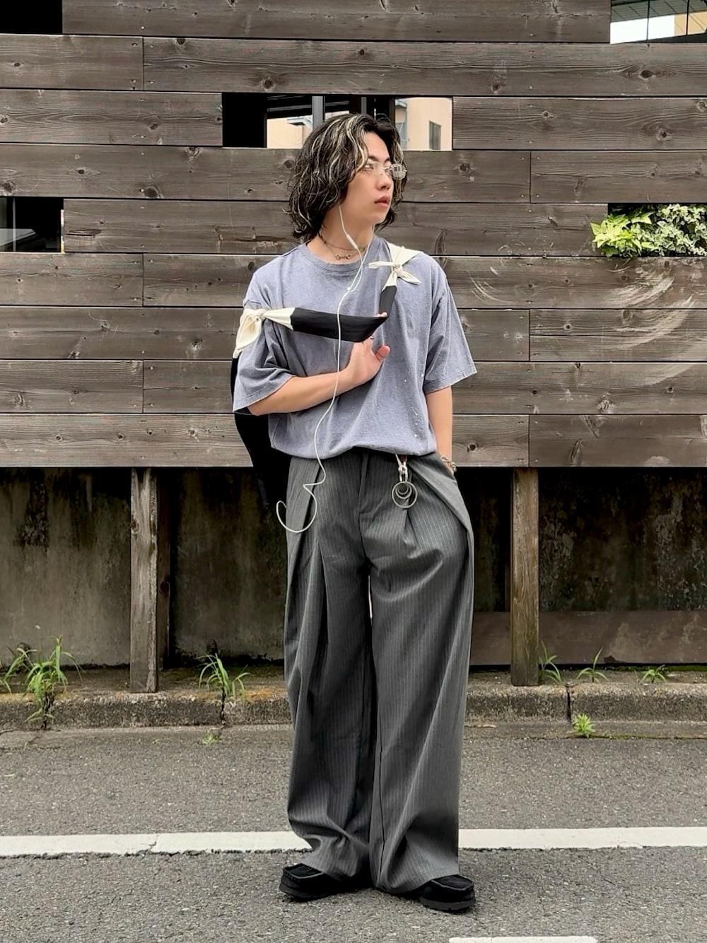 グレー系のスラックス、ブルー系のTシャツ/カットソー、ブラック系のスニーカーを着用したメンズの夏コーディネートの1枚目の写真