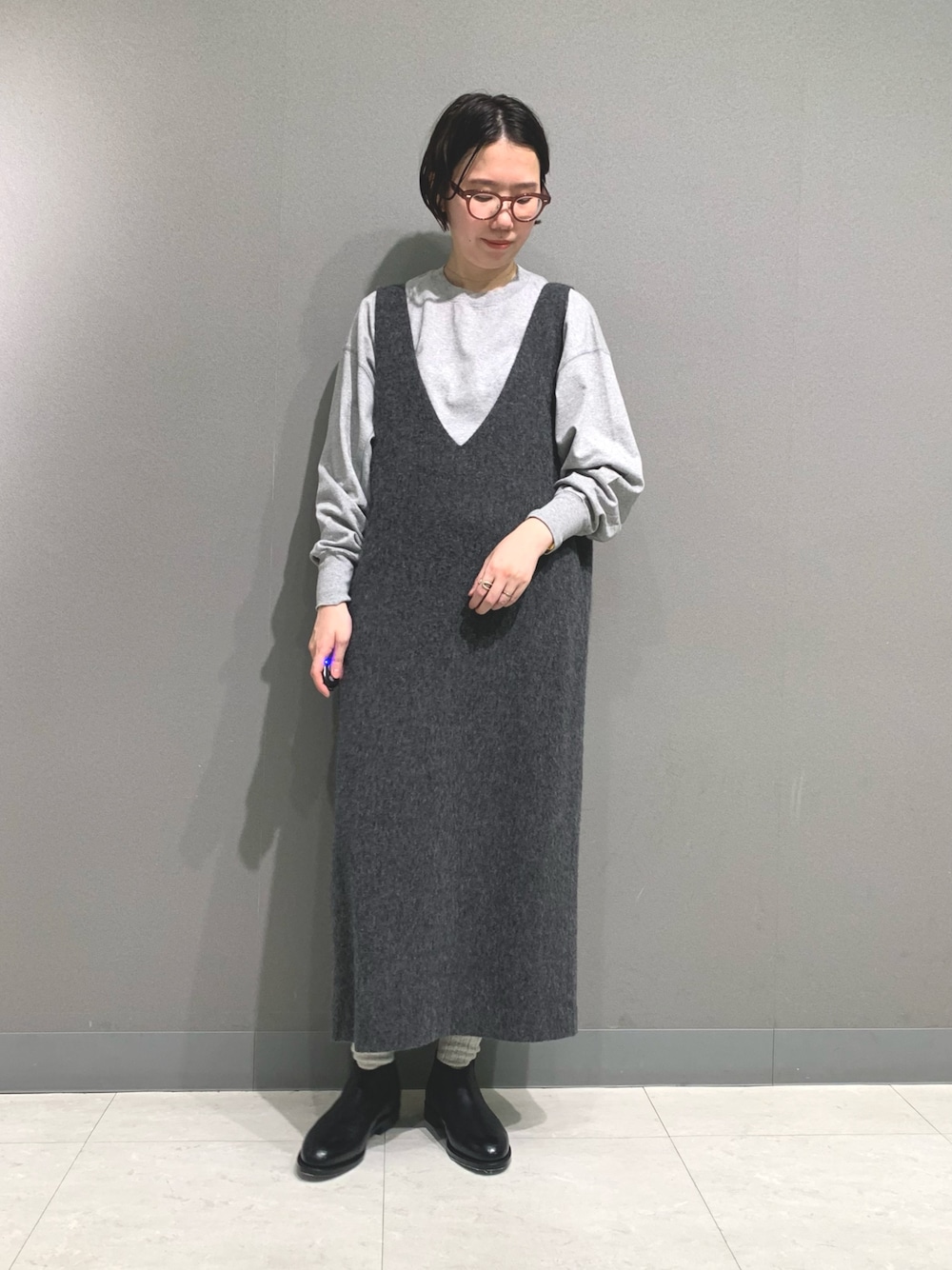 グレー系のTシャツ/カットソー、グレー系のワンピース、ブラック系のブーツを着用したレディースの秋コーディネートの1枚目の写真