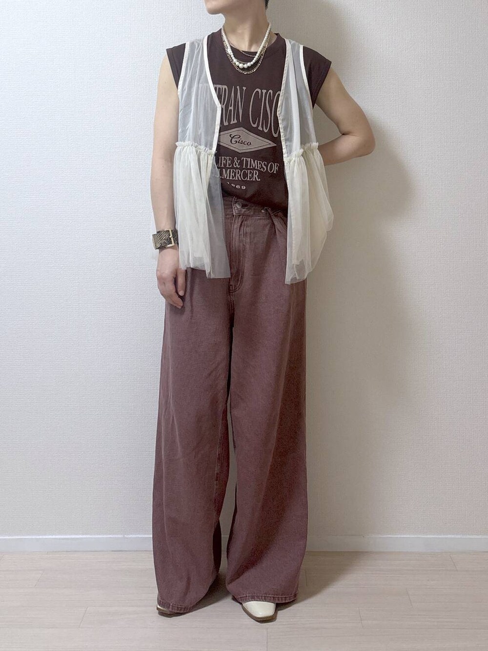 ベージュ系のベスト、ブラウン系のデニムパンツを着用したレディースの夏コーディネートの1枚目の写真