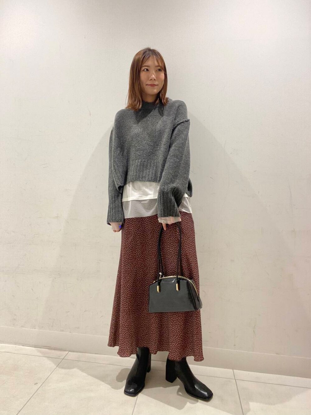 ブラック系のブーツ、ブラック系のハンドバッグ、ブラウン系のスカートを着用したレディースの冬コーディネートの1枚目の写真