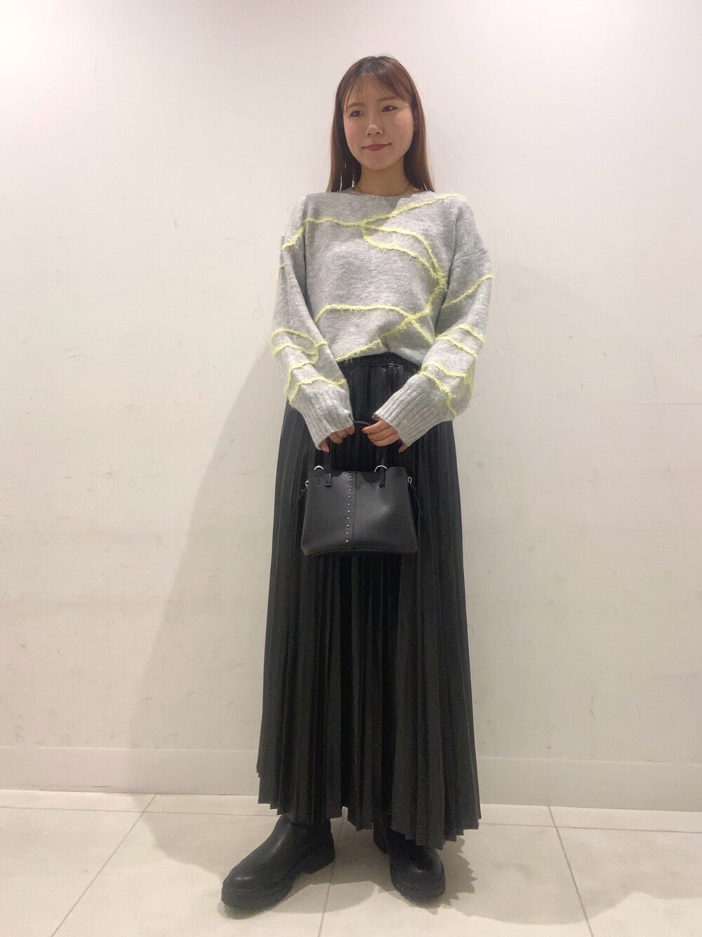 グレー系のニット/セーター、ブラック系のスカート、ブラック系のショルダーバッグを着用したレディースの秋コーディネートの1枚目の写真