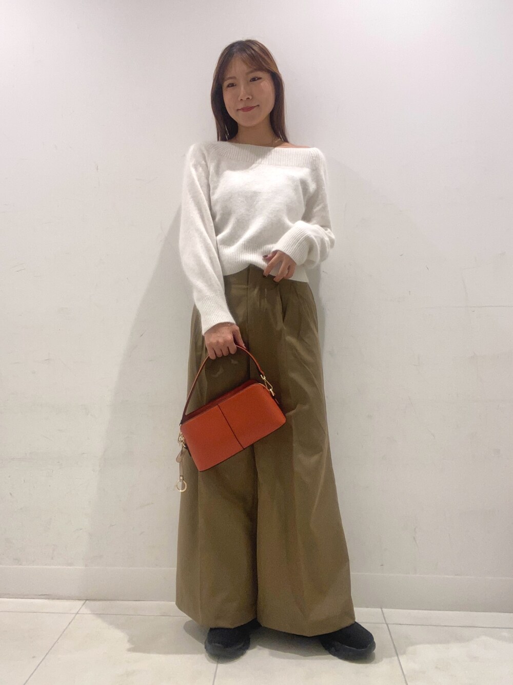 ホワイト系のニット/セーター、ベージュ系のその他パンツ、オレンジ系のショルダーバッグを着用したレディースの秋コーディネートの1枚目の写真