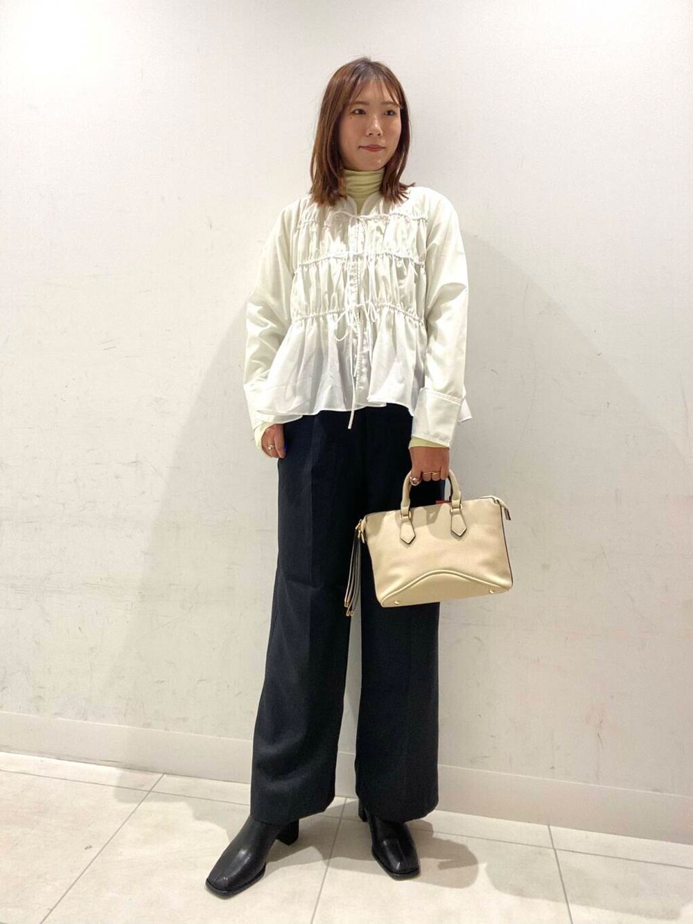 ホワイト系のボストンバッグ、ブラック系のブーツ、グレー系のその他パンツを着用したレディースの冬コーディネートの1枚目の写真