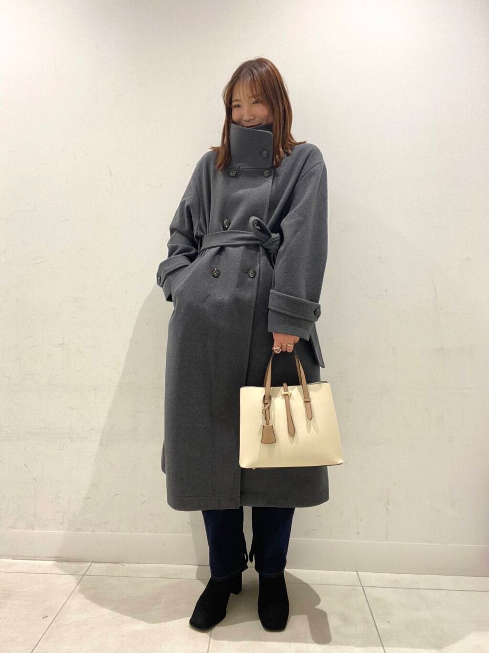 ホワイト系のトートバッグ、ブラック系のブーツ、グレー系のその他アウターを着用したレディースの冬コーディネートの1枚目の写真