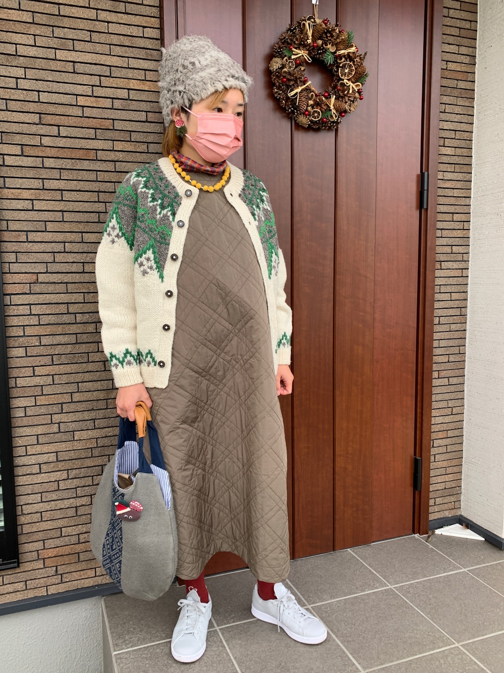 ベージュ系のカーディガン/ボレロ、グリーン系のワンピース、レッド系のTシャツ/カットソーを着用したレディースの冬コーディネートの1枚目の写真