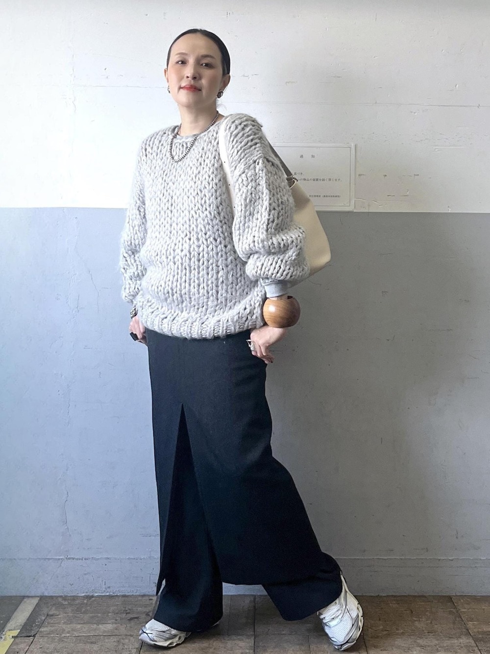 ブラック系のスカート、ホワイト系のショルダーバッグ、ホワイト系のスニーカーを着用したレディースの冬コーディネートの1枚目の写真