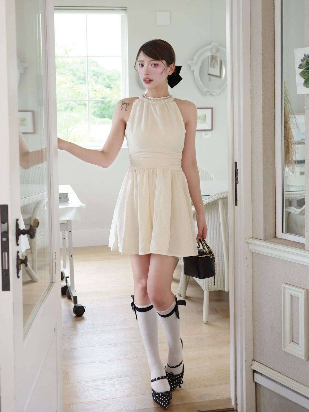 ホワイト系のワンピース、ブラック系のショルダーバッグ、ブラック系のパンプスを着用したレディースの夏コーディネートの1枚目の写真