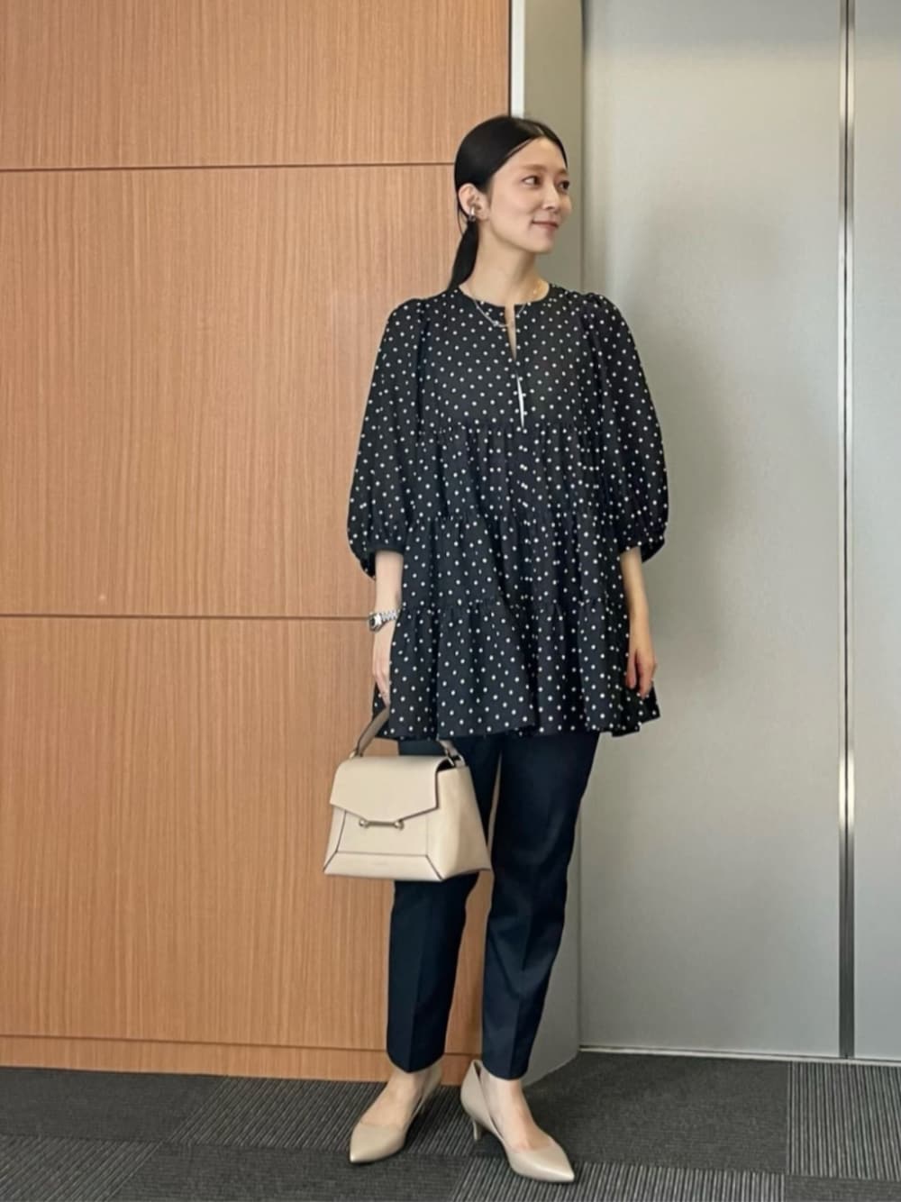 グレー系のスラックス、ベージュ系のパンプスを着用したレディースの春コーディネートの1枚目の写真