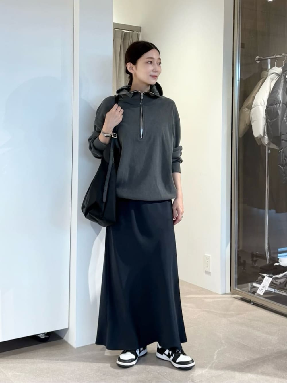 ブルー系のスカート、ブラック系のトートバッグを着用したレディースの秋コーディネートの1枚目の写真