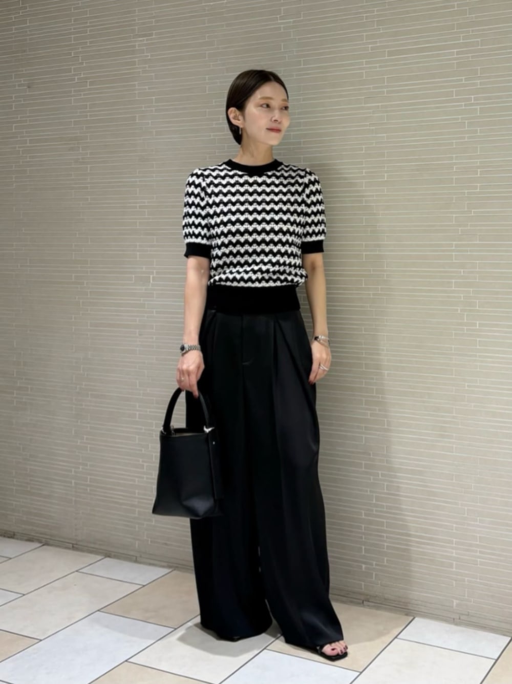 ブラック系のその他パンツ、ブラック系のニット/セーター、ブラック系のサンダルを着用したレディースの春コーディネートの1枚目の写真