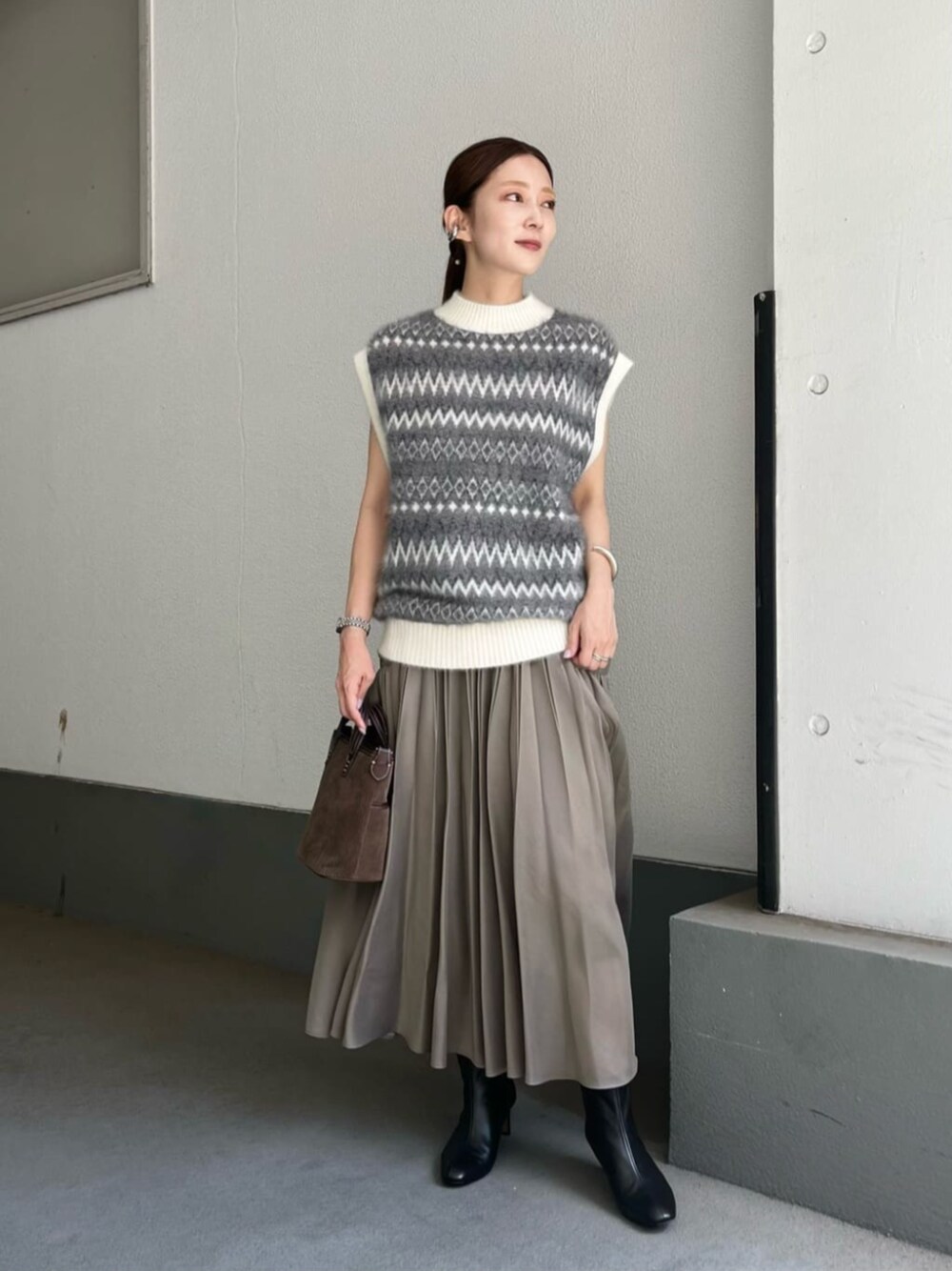 グリーン系のスカート、グレー系のベストを着用したレディースの夏コーディネートの1枚目の写真