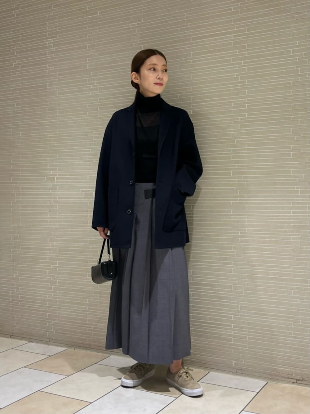 ブラック系のニット/セーター、グレー系のスカートを着用したレディースの秋コーディネートの1枚目の写真