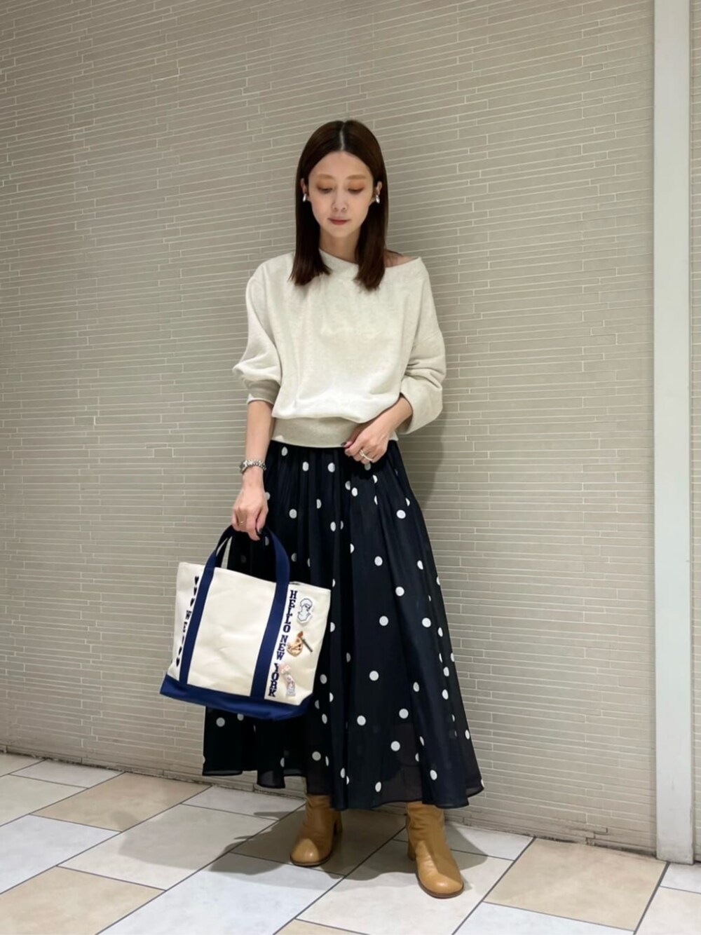 ブラック系のスカート、ベージュ系のブーツ、ホワイト系のスウェットを着用したレディースの秋コーディネートの1枚目の写真