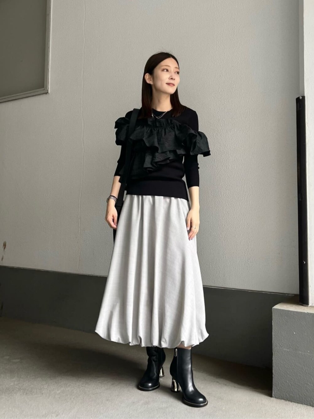 ブラック系のニット/セーター、グレー系のスカートを着用したレディースの夏コーディネートの1枚目の写真