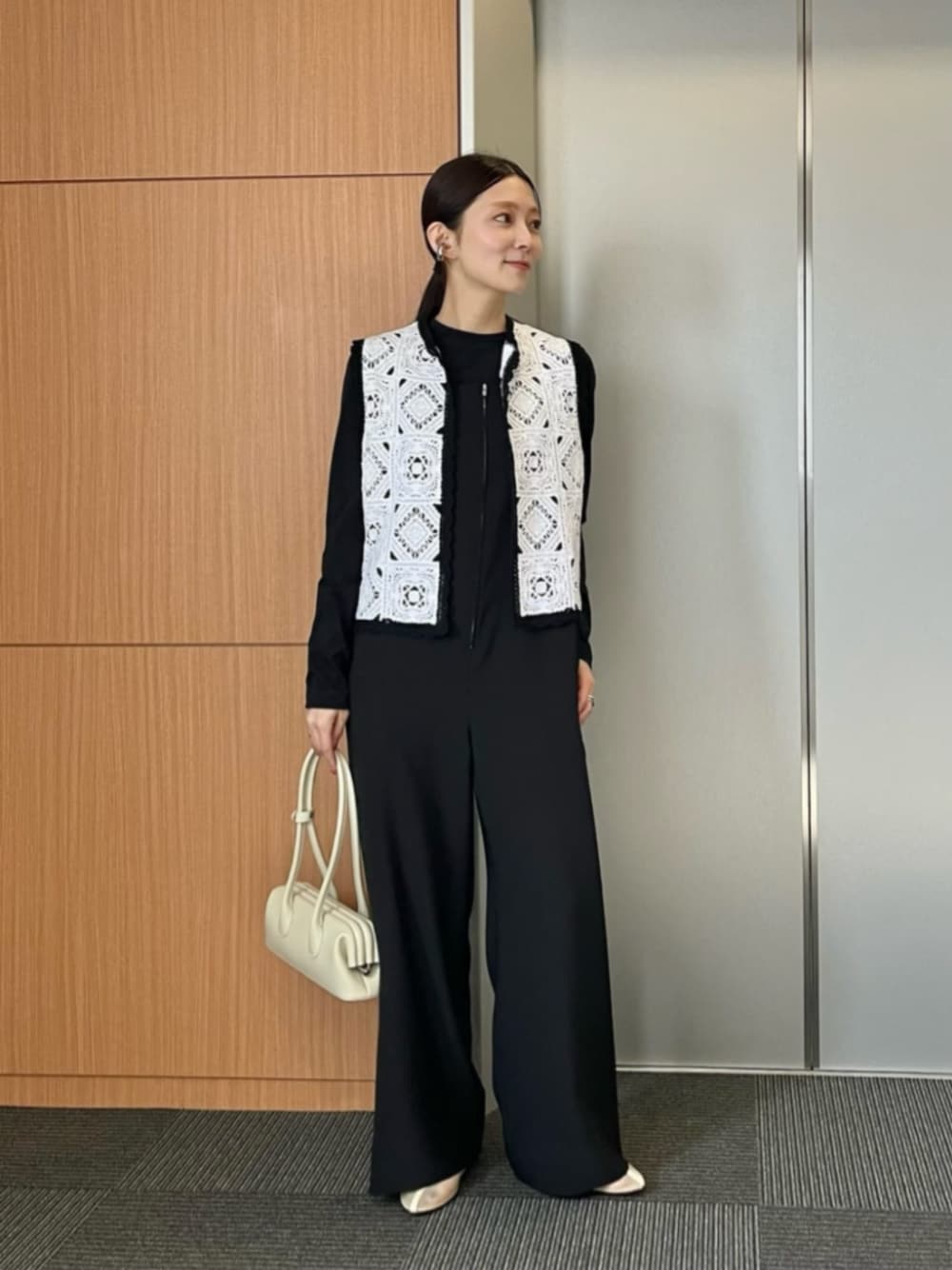 ホワイト系のベスト、ベージュ系のサンダル、ホワイト系のショルダーバッグを着用したレディースの冬コーディネートの1枚目の写真