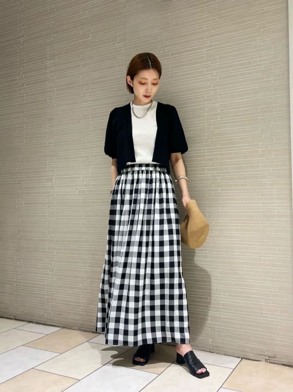 ブラック系のサンダル、ブラック系のスカート、ホワイト系のTシャツ/カットソーを着用したレディースの春コーディネートの1枚目の写真