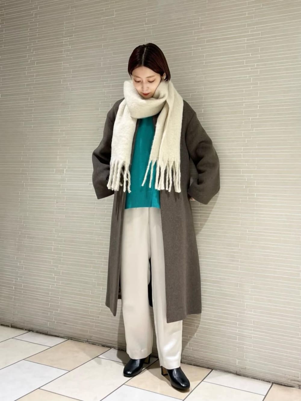 ホワイト系のその他パンツ、グリーン系のニット/セーター、ブラウン系のノーカラーコートを着用したレディースの冬コーディネートの1枚目の写真